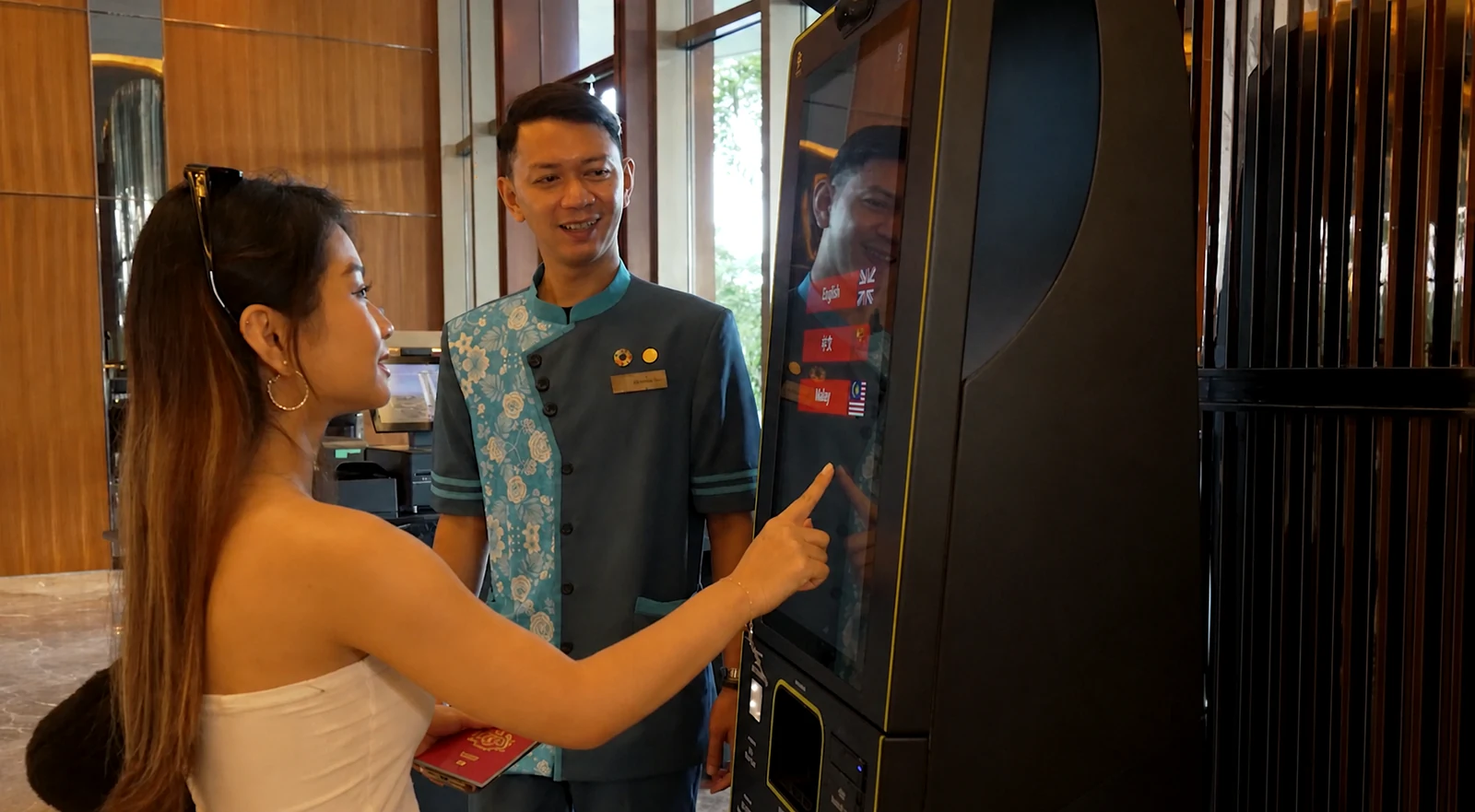 Hotel guest using a self-service terminal with assistance from a hotel team member