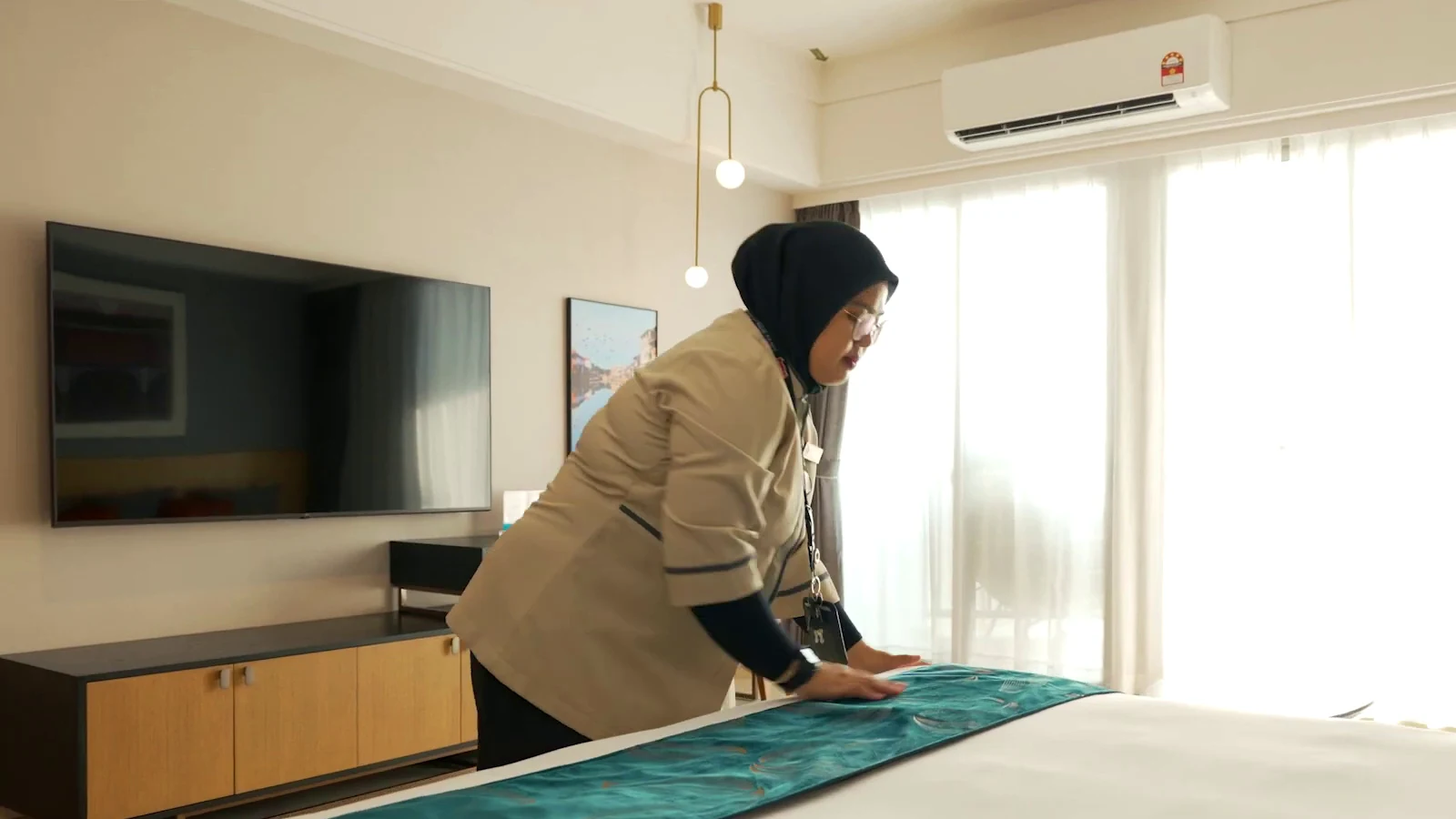 Hotel team member preparing a guest room in a real property