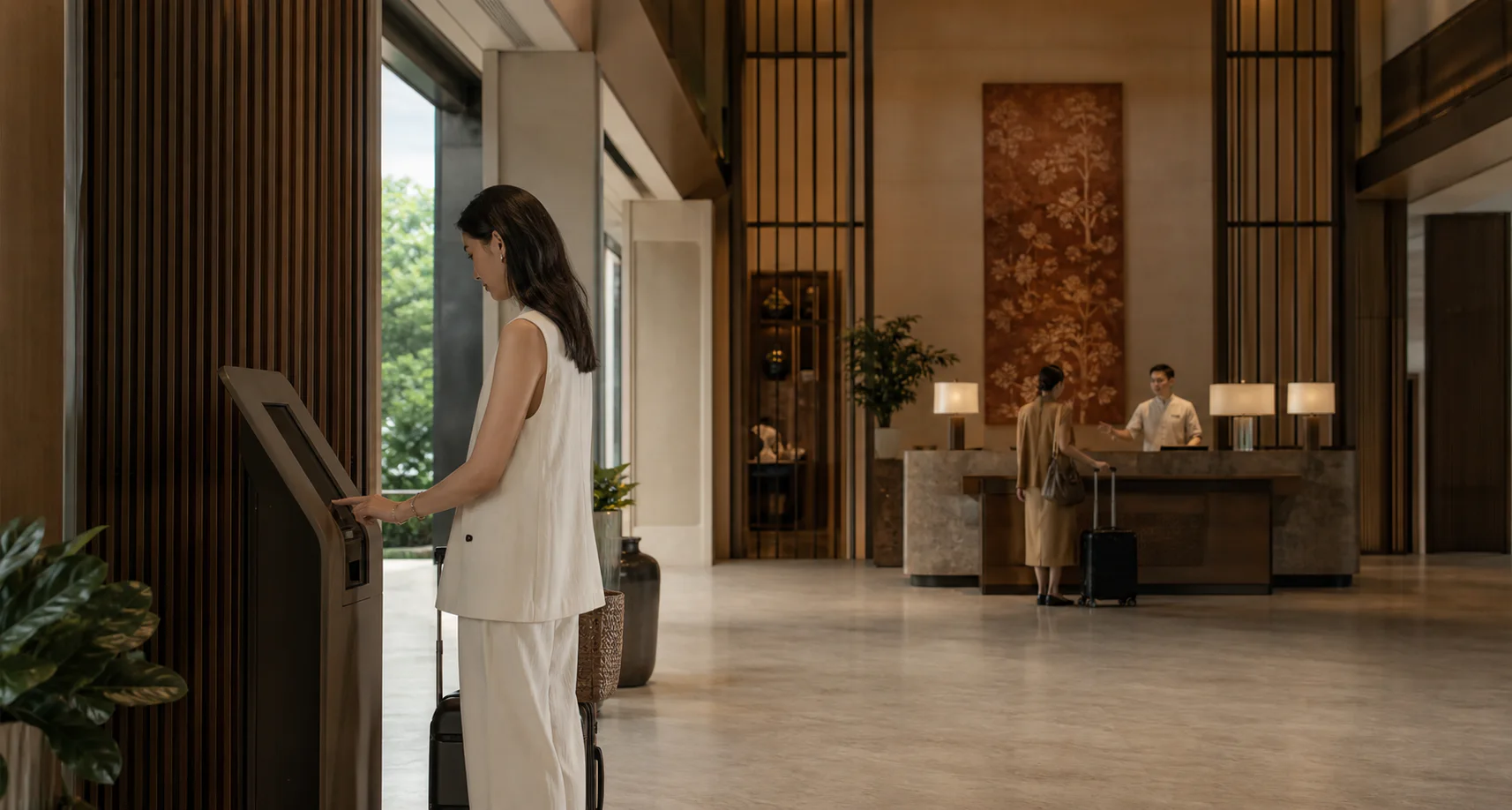 Hotel guest using a self-service check-in kiosk in a modern lobby